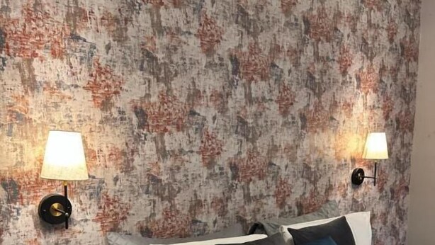A bedroom with a bed, two bedside lamps, a nightstand, and a textured wall. - Pasha Hotel London (London)
