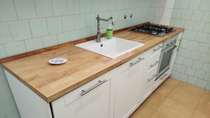 Una cocina con encimera de madera, armarios blancos, un lavamanos, una estufa a gas y un plato pequeño sobre la encimera.