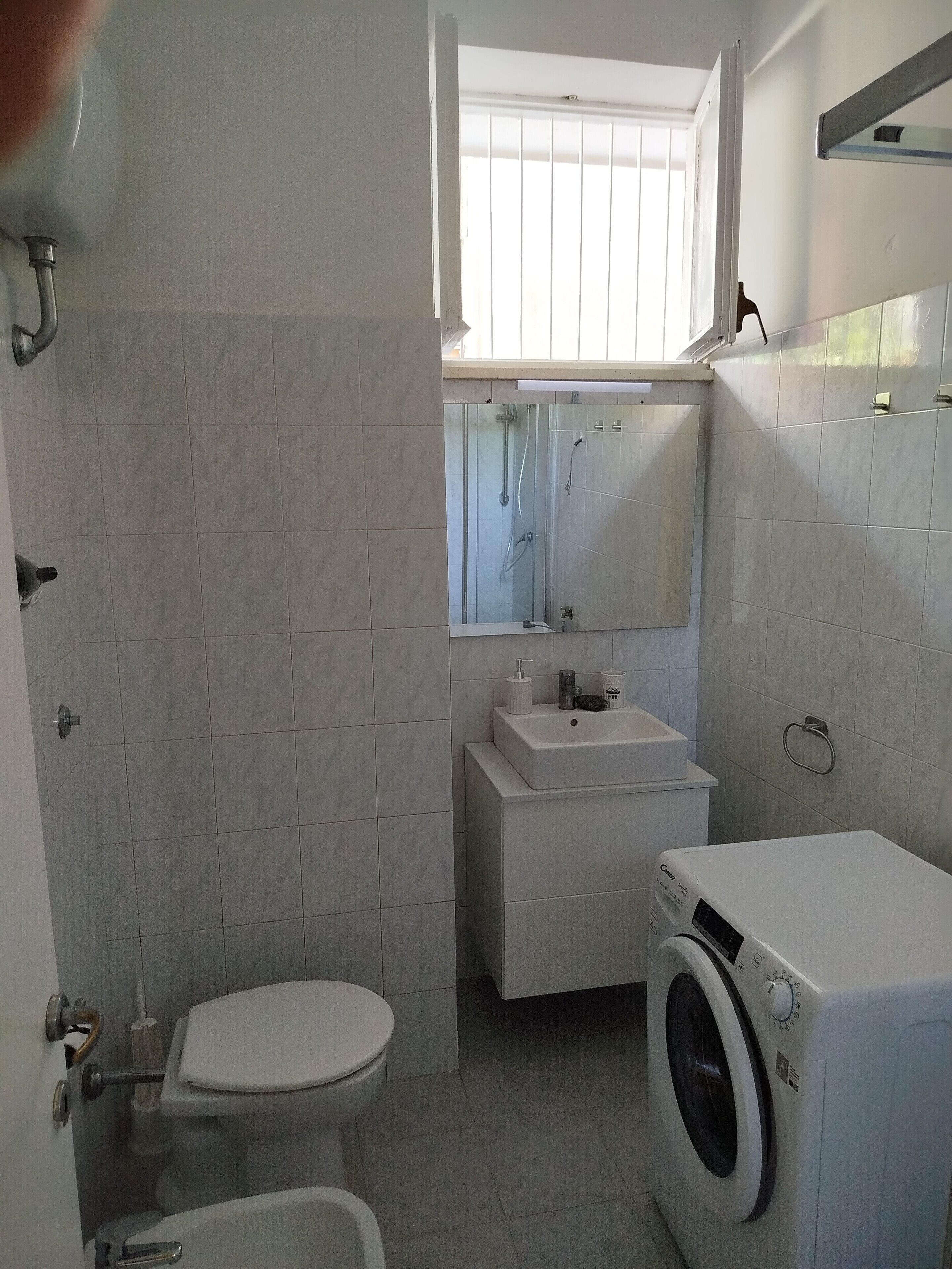 A compact bathroom with a toilet, sink, and washing machine.