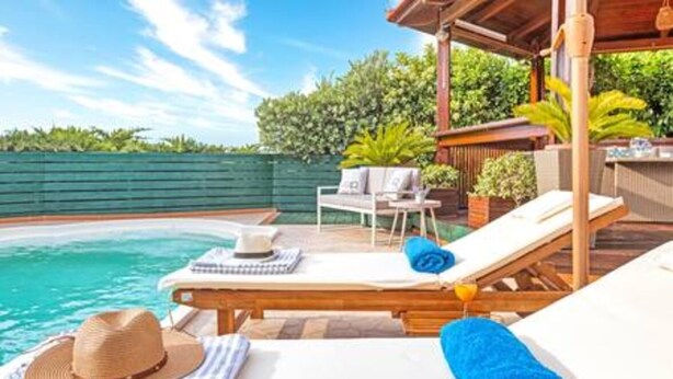 A poolside area with lounge chairs, a table with a hat and towel, and a view of the pool. - Villa Stachy & Elia with Heated Pool, by Estia (Malevizi)