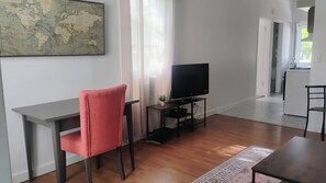 A modern living room with a flat-screen TV, a red chair, a small table, and a map on the wall.