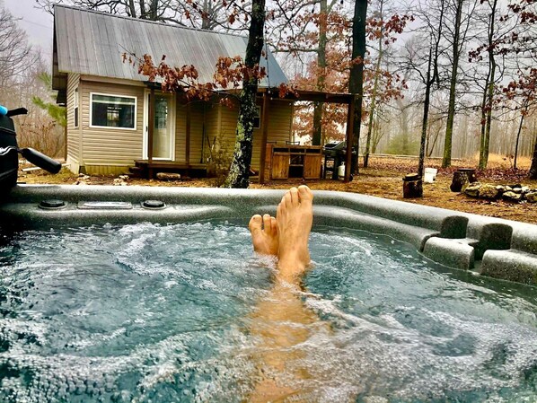 A hot tub with a wooden deck and a house in the background.