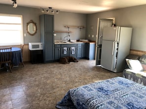 A compact kitchen with a microwave, sink, and refrigerator, a dining area with a table and chairs, and a sleeping area with a bed. - Tranquil Lakefront Cabin Surrounded by Woods, Wildlife & Scenic Trails in  Williford, Arkansas (Williford)