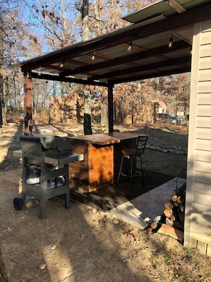 An outdoor patio with a grill, bar counter, and seating area. - Tranquil Lakefront Cabin Surrounded by Woods, Wildlife & Scenic Trails in  Williford, Arkansas (Williford)