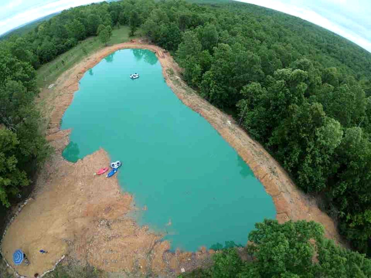 An aerial view of a natural lake surrounded by dense forest.