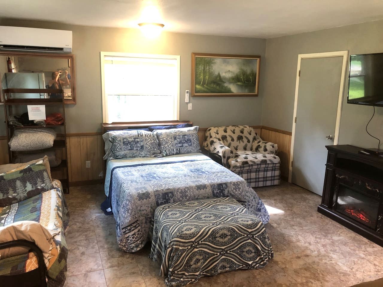 Une chambre à coucher avec un lit, une chaise, une cheminée et un tableau au mur.