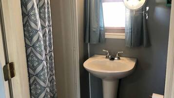 A bathroom with a shower curtain, a sink, a mirror, and a toilet.