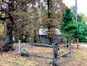 A rustic cabin surrounded by trees, a wooden fence, and a utility pole. - Tranquil Lakefront Cabin Surrounded by Woods, Wildlife & Scenic Trails in  Williford, Arkansas (Williford)