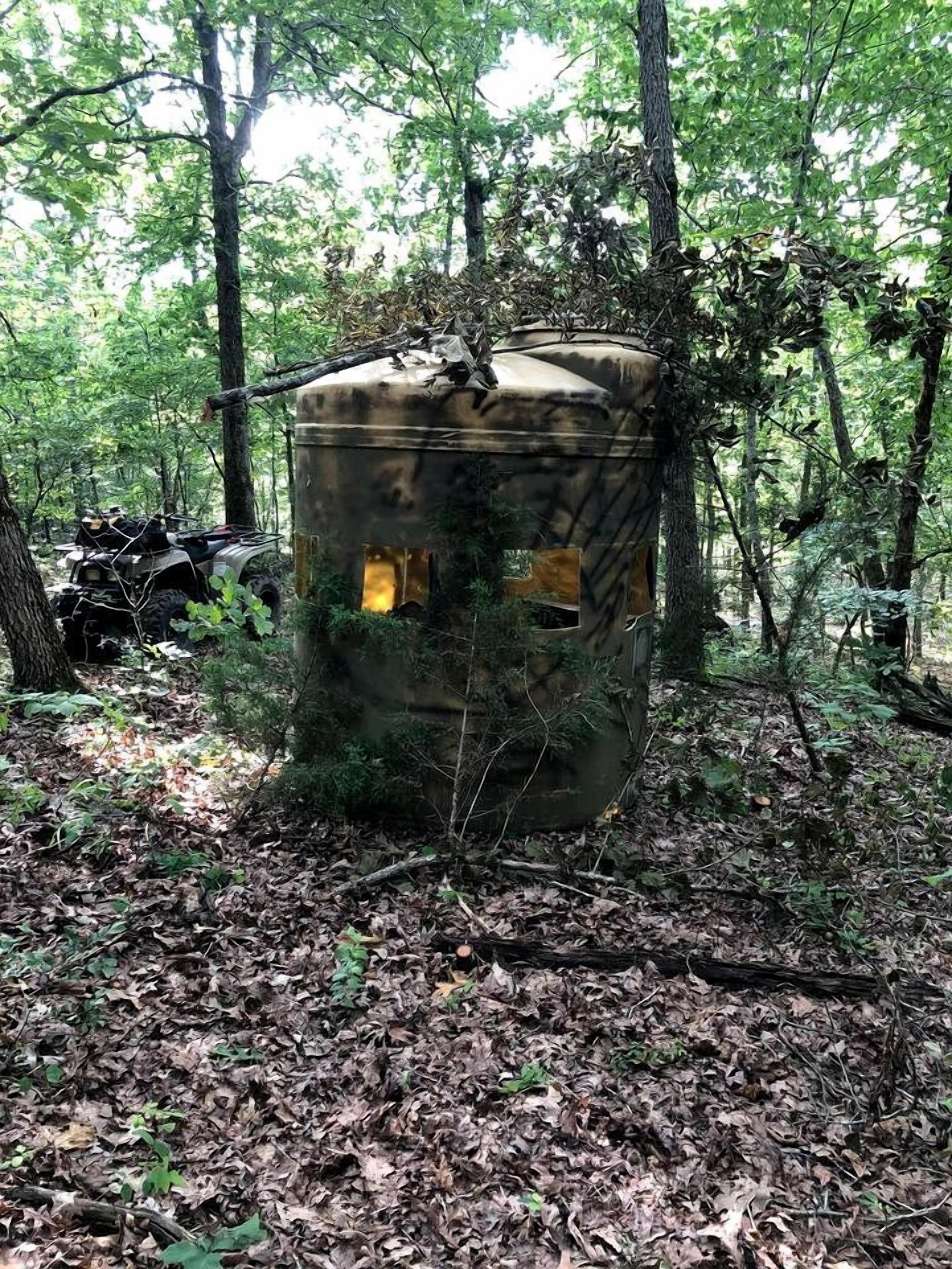 A cylindrical structure in a forest, surrounded by trees and foliage.