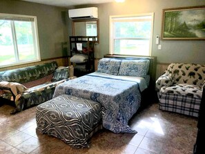 Ein Schlafzimmer mit Bett, Stuhl, Bank und Fenster.