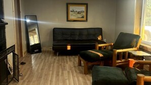 Ein Wohnzimmer mit einer Couch, Sesseln, einem gerahmten Bild an der Wand und einem Fenster.