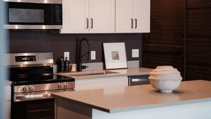 Une cuisine moderne dotée d’appareils électroménagers en acier inoxydable, d’un plan de travail en marbre et d’un vase décoratif.