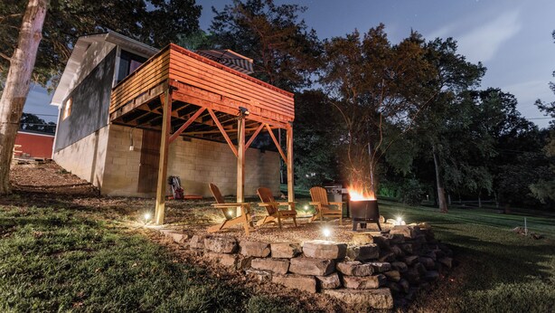 A wooden deck with chairs, a fire pit, and a stone wall. - The Hideaway on Table Rock Lake (Reeds Spring)