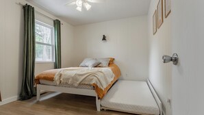 A bedroom with a bed, a window with curtains, a wall-mounted light, and a ceiling fan. - The Hideaway on Table Rock Lake (Reeds Spring)