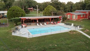 A swimming pool with a covered area, lounge chairs, and a fenced deck. - The Hideaway on Table Rock Lake (Reeds Spring)