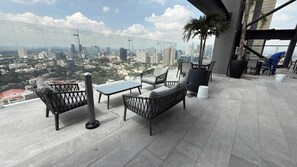 A rooftop terrace with a table and chairs, a potted plant, and a view of the cityscape.
