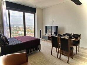 A modern hotel room with a bed, a dining table with chairs, a TV, and a view of a cityscape. - Studio in Anzures w/ Views, Gym & Jacuzzi (Ciudad de México)