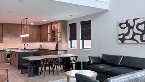 A modern apartment with a dining area, kitchen, and a black leather sofa. - Modern luxury in Historic Downtown McKinney (McKinney)