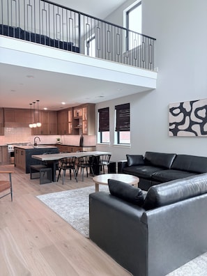 A modern apartment with a dining area, kitchen, and a black leather sofa. - Modern luxury in Historic Downtown McKinney (McKinney)