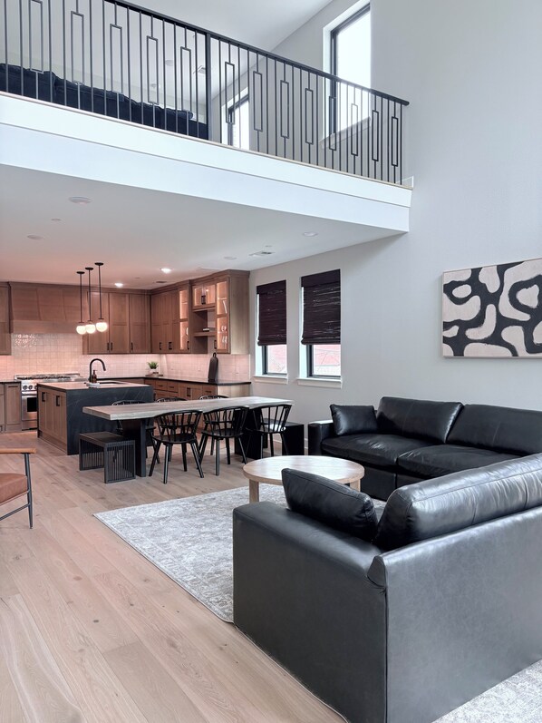 Un appartement moderne comprenant un coin repas, une cuisine et un canapé en cuir noir.