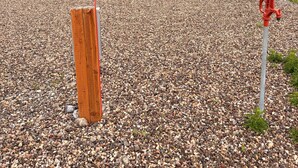 A gravel area with a wooden post and a red fire hydrant.