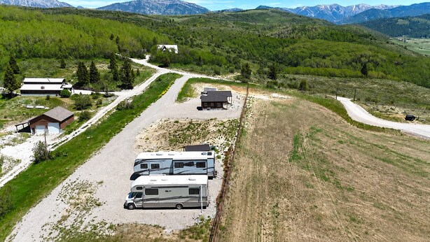 A campground with RVs, a gravel parking area, and buildings in a mountainous landscape.