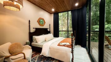 A bedroom with a large window, a bed, a chair, and a rug.