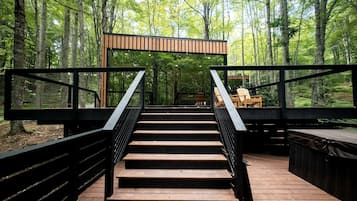 A wooden staircase leading to a platform with a railing, surrounded by a forest.