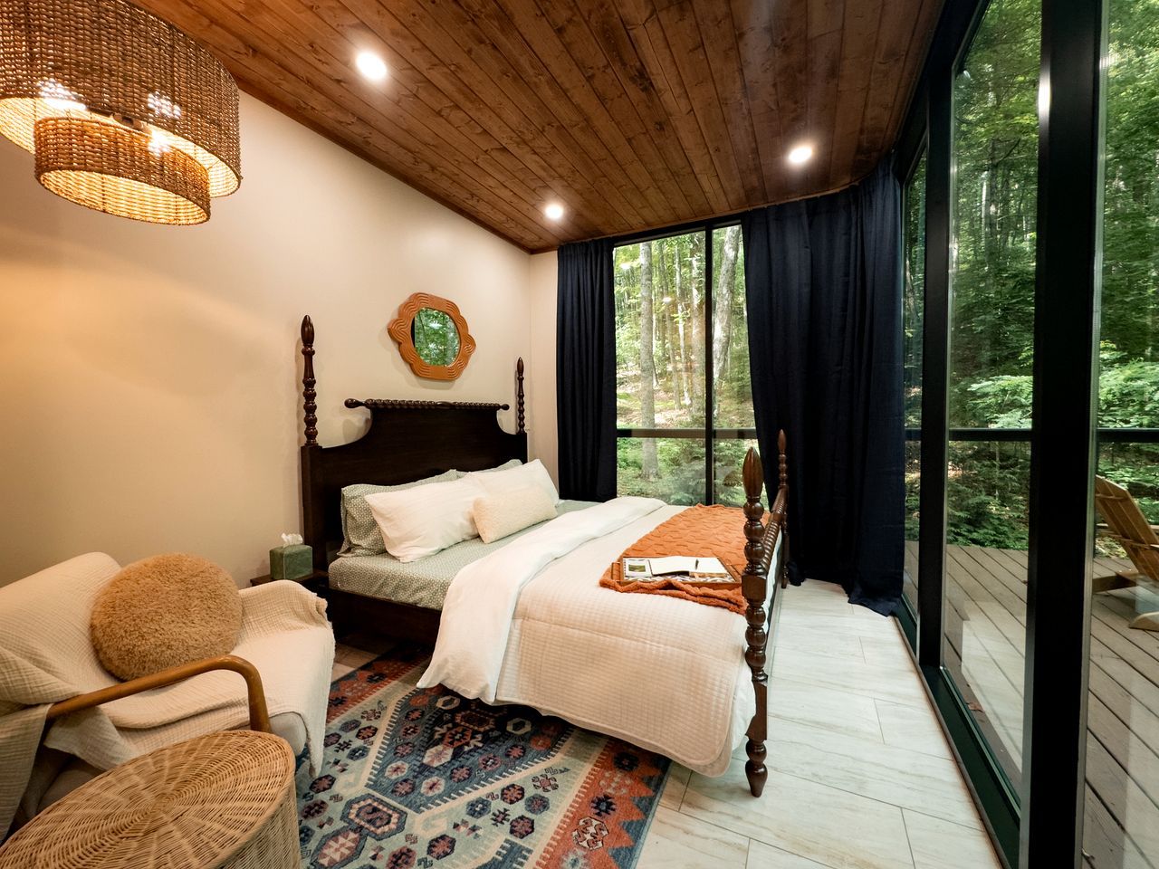Une chambre avec une grande fenêtre, un lit, une chaise et un tapis.