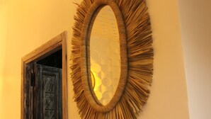 Ein Zimmer mit Holztür, strukturierter Wand und rundem Spiegel mit Fransenmuster.