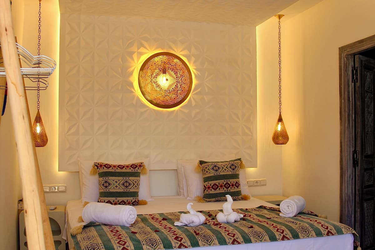 A room with a bed, hanging lamps, and a patterned wall.