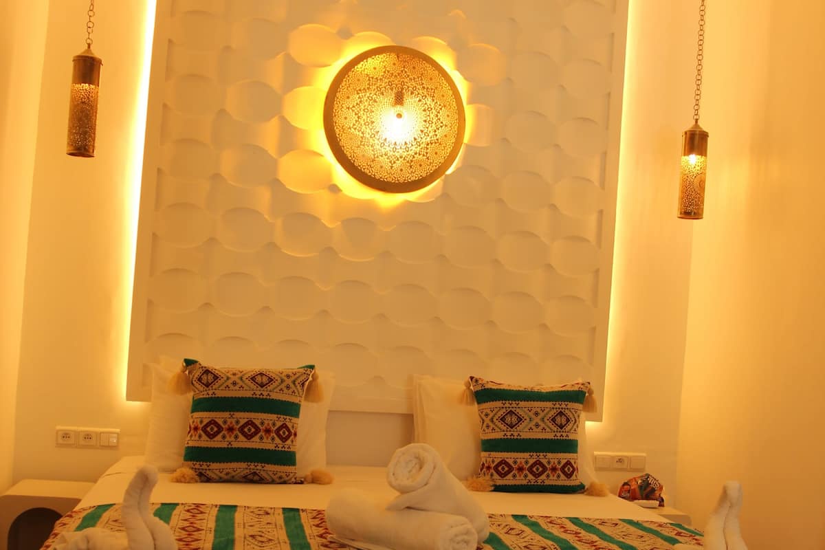 A bed with patterned bedding, a wall-mounted light fixture, and a textured wall design.