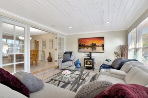 A living room with a sofa, a glass coffee table, a fireplace, and a painting on the wall. - Casa by The Cove 3BR 2BA plus Office (Deerfield Beach)