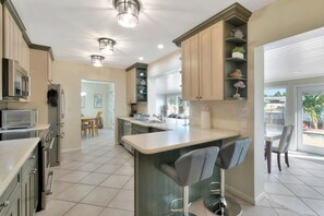 A kitchen with a bar area, a dining area, and a view of the outdoors. - Casa by The Cove 3BR 2BA plus Office (Deerfield Beach)