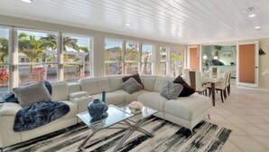 Ein modernes Wohnzimmer mit einem Ecksofa, einem Glastisch und einem Essbereich mit Tisch und Stühlen.