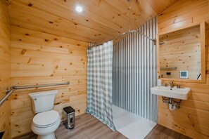 Puisilla paneeleilla verhoiltu kylpyhuone, jossa on wc, ruutukuviollinen suihkuverho, pesuallas ja peili.