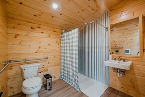 A wooden-paneled bathroom with a toilet, a shower with a checkered curtain, a sink, and a mirror.