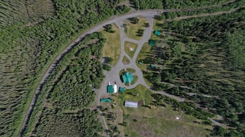 An aerial view of a property with a central building surrounded by forested areas and a winding road.