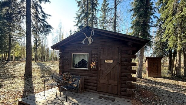 Una cabaña rústica con fachada de madera, una ventana, una puerta y un letrero que dice 'DUKE'.