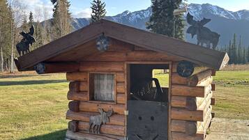 A wooden cabin with a door open, a window, and a small porch.