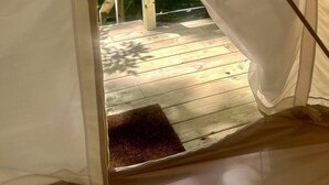 Una carpa con una terraza de madera y una puerta.
