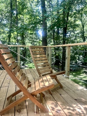 A wooden deck with two wooden lounge chairs.