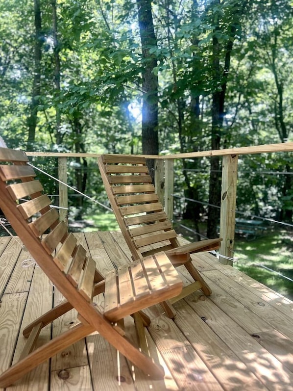 A wooden deck with two wooden lounge chairs.