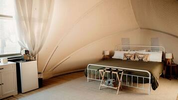 Un dormitorio tipo tienda de campaña con una cama litera, un escritorio y una silla.