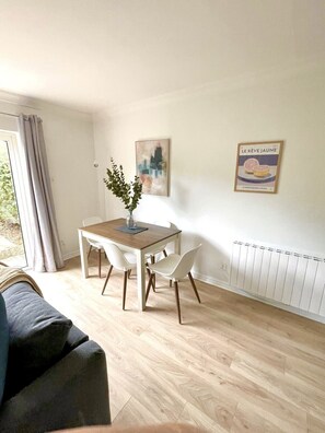 A dining area with a wooden table and white chairs, a vase with greenery, a cityscape painting, and a poster on the wall. - Luxury By The Coast 9 (Galway)