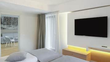 Quarto de hotel moderno com uma cama, uma televisão na parede e vista para uma paisagem nevada pela janela.
