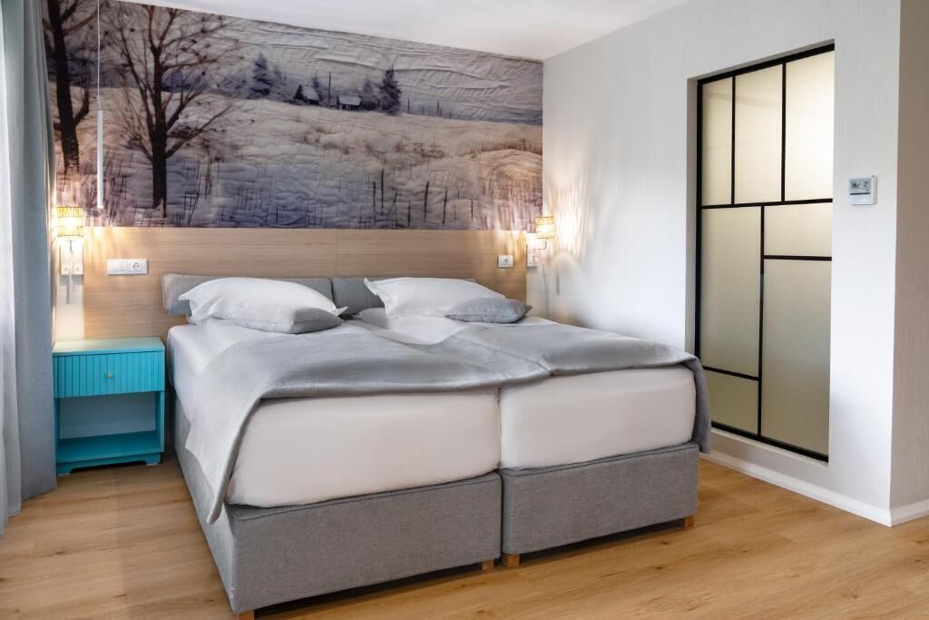 A bedroom with a bed, bedside tables, a wall-mounted light, and a sliding door.