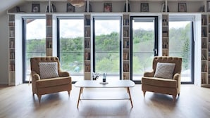 Una habitación con dos sillones, una mesa de centro y un ventanal con vistas a zonas verdes.