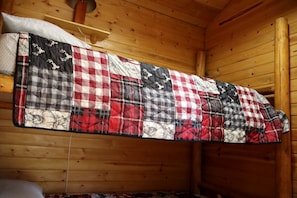 A wooden cabin interior with a quilted blanket hanging on the wall. - Family-Friendly Vacation Rental for Four near Missoula, Montana (Hall)
