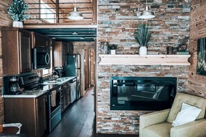 A modern kitchen with stainless steel appliances, a wooden ceiling, and a brick wall. - Impressive Tiny House Rental for Great Mountain Getaways in Colorado (Mesa)
